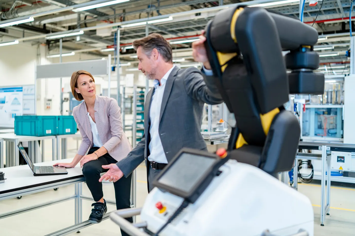 Une ingénieure et un responsable d'atelier discutent près d'un robot collaboratif