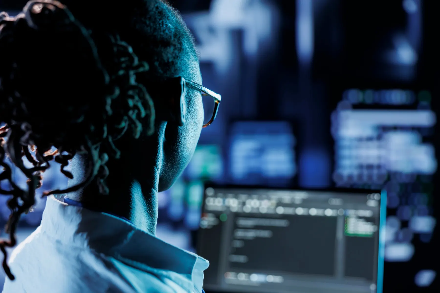 Ingénieure analysant du code devant plusieurs écrans