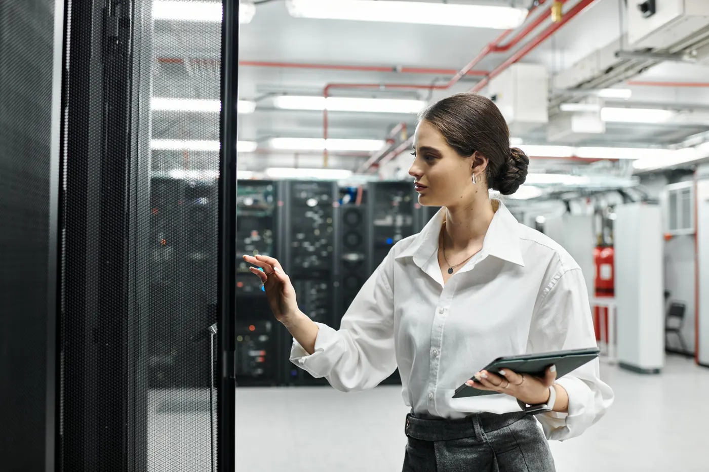 Ingénieure inspectant une baie dans un datacenter, tablette en main