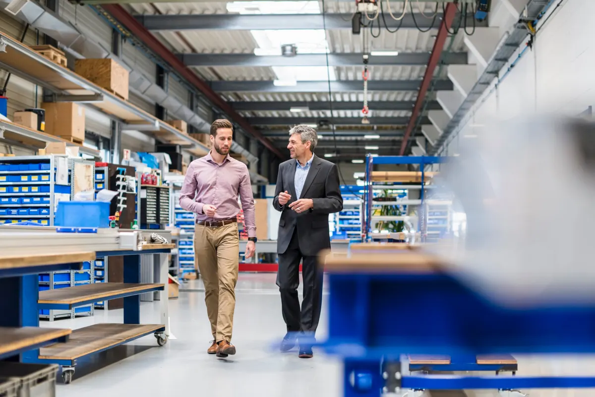 Deux responsables échangent en marchant dans un atelier logistique